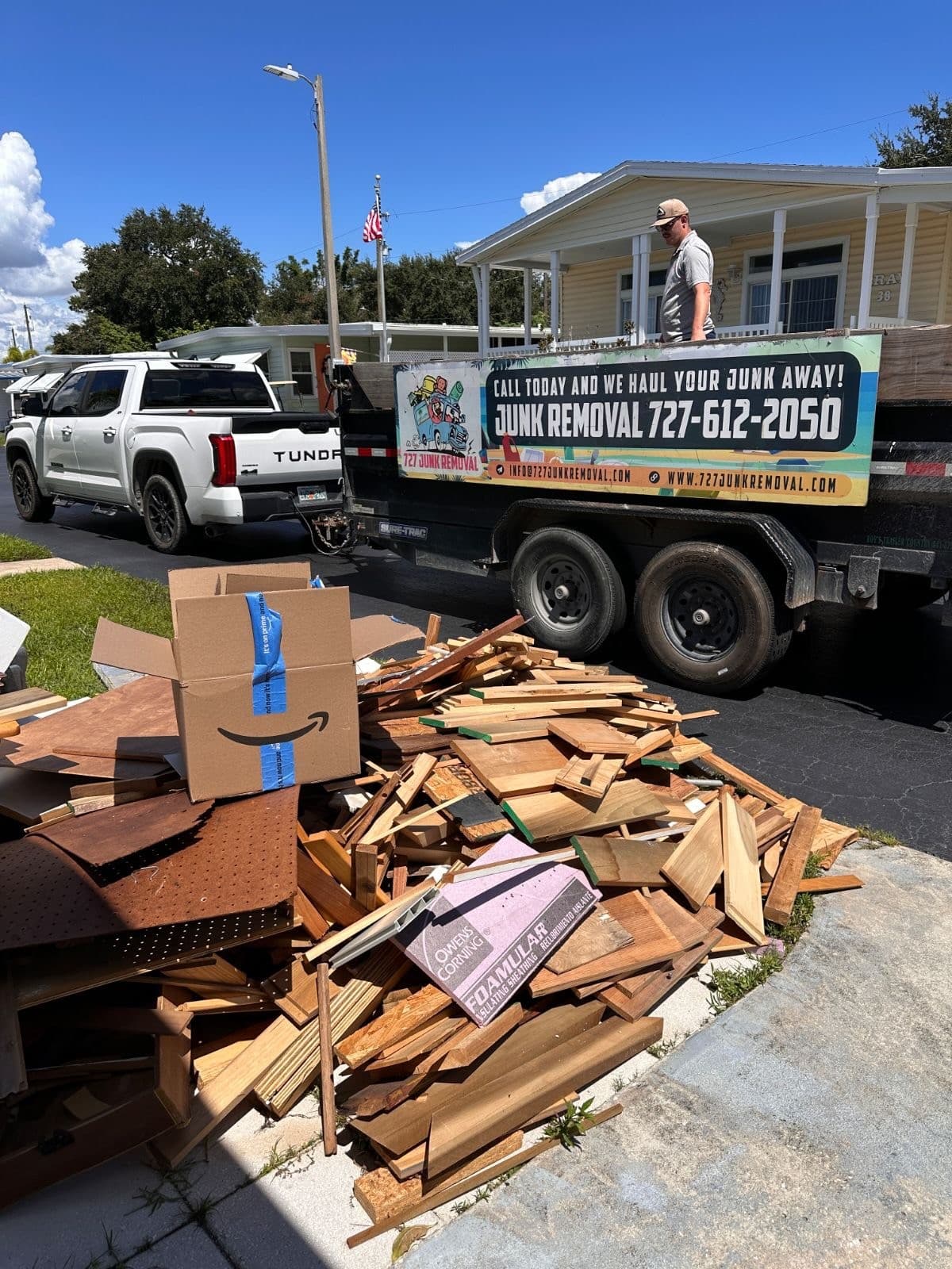 727 Junk Removal trailer in a Largo driveway next to a construction debris pile