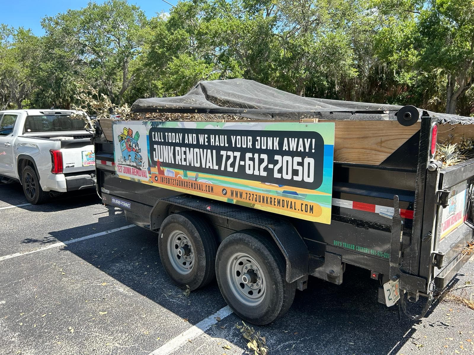 727 Junk Removal dump trailer loaded with yard debris, netted and ready to haul